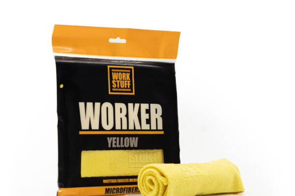 Un paño de limpieza de microfibra amarillo, parcialmente enrollado, se encuentra delante de un embalaje negro y naranja con la etiqueta WORKER YELLOW de Work Stuff. Un paño de limpieza de microfibra amarillo, parcialmente enrollado, se encuentra delante de un embalaje negro y naranja con la etiqueta WORKER YELLOW de Work Stuff.