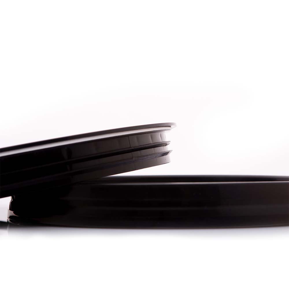 Two black, round HDPE bucket lids are displayed on a white background, one leaning at an angle against the other.