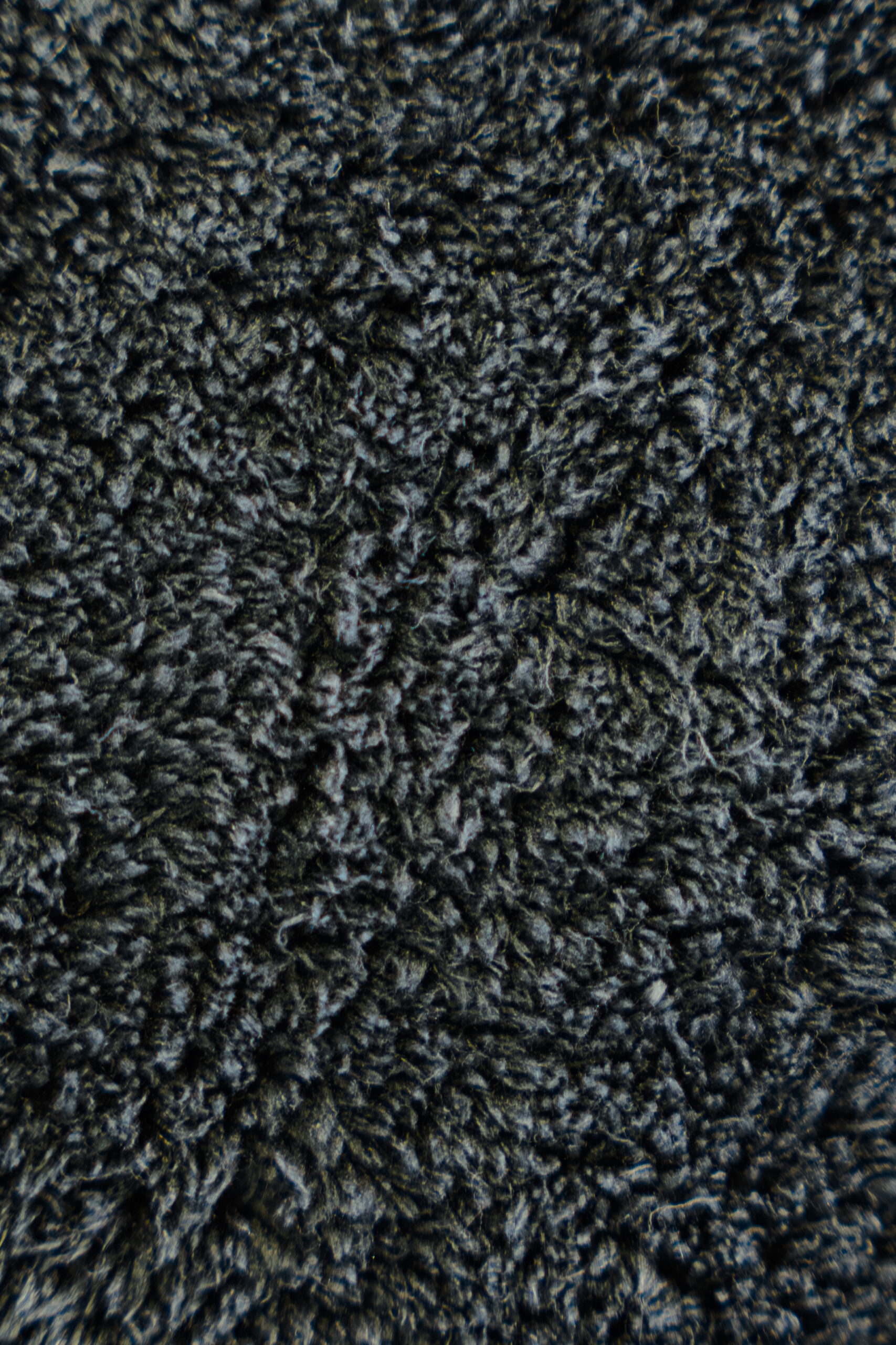 Textured, dark gray, soft fabric surface with dense, slightly shiny fibers resembling plush fleece or carpet.