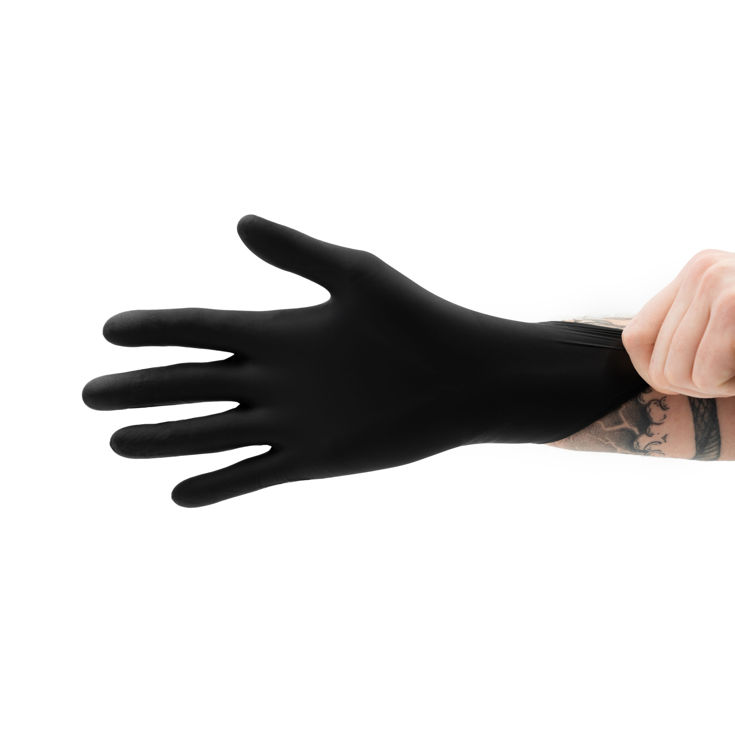 A tattooed arm pulls on a black nitrile detailing glove, stretching it over their hand against a white background.