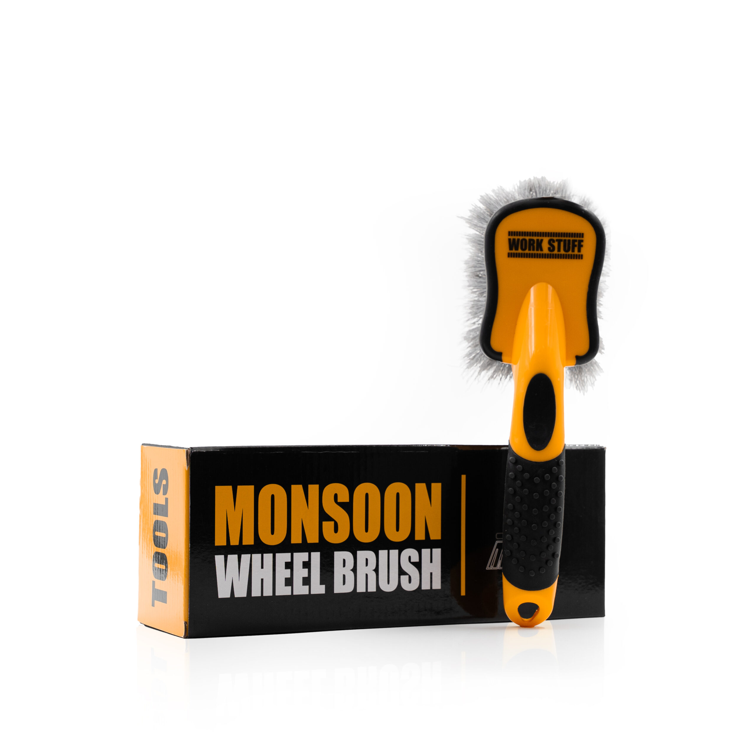 Une brosse à roue Monsoon orange et noire avec des poils blancs est posée sur sa boîte noire et orange étiquetée MONSOON WHEEL BRUSH TOOLS.