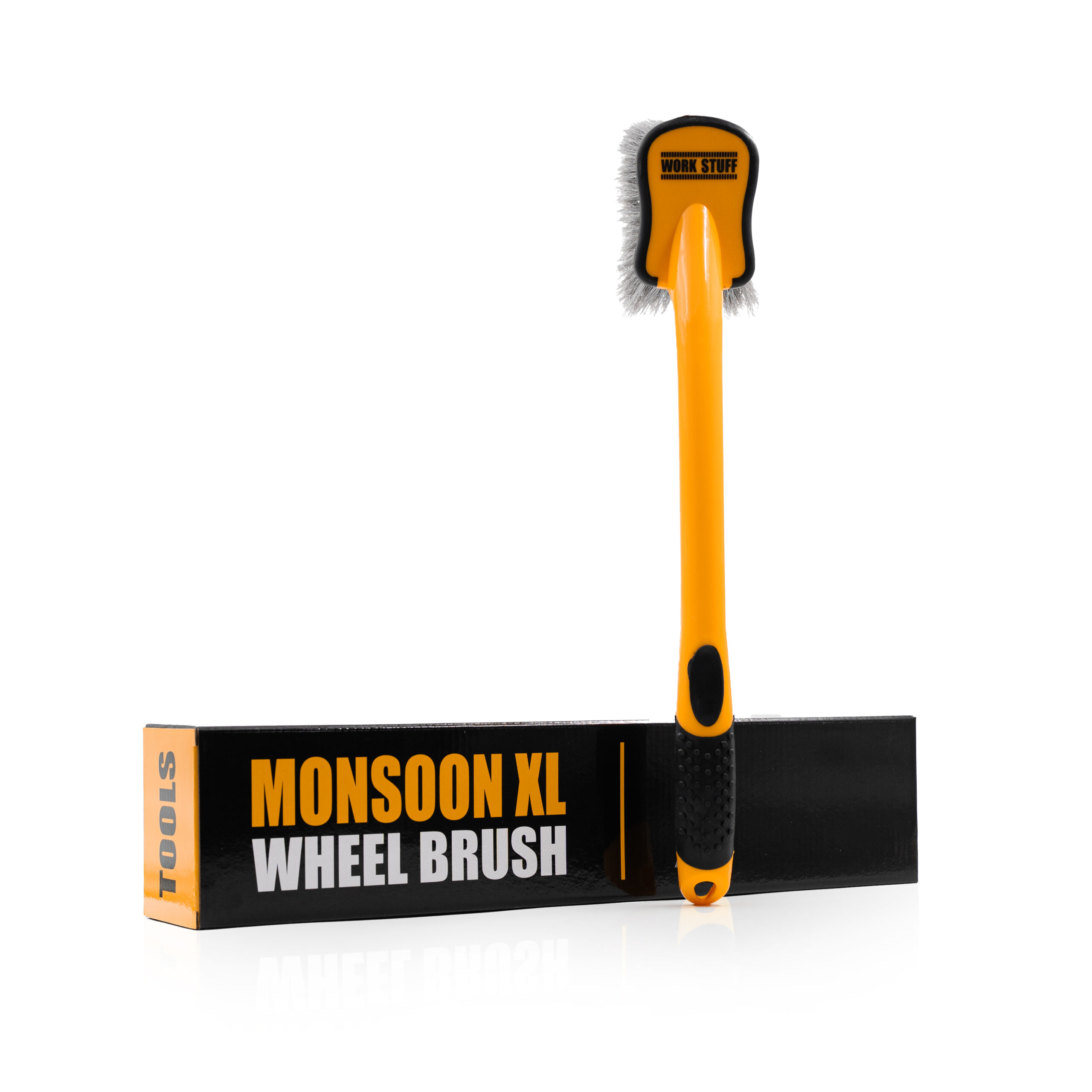 Une brosse à roue jaune et noire avec des poils blancs se tient debout sur une boîte MONSOON XL WHEEL BRUSH ; le manche est texturé.