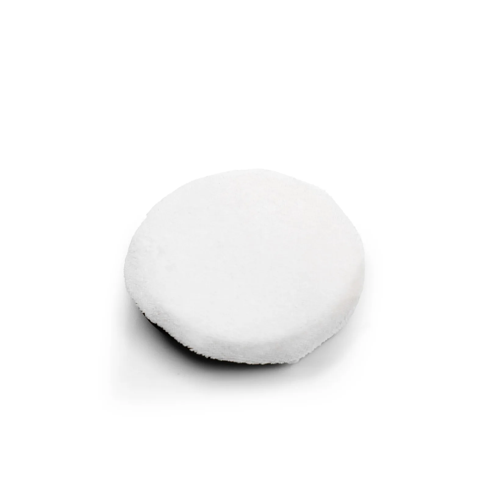 Une éponge ou un tampon rond et blanc, à la texture douce, posé sur un fond blanc uni.